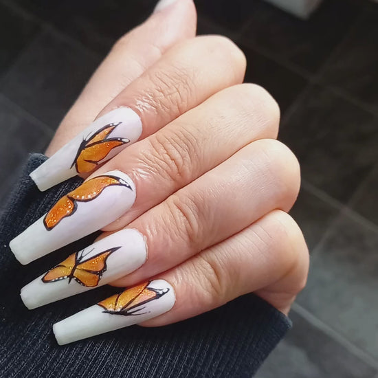 uks best press on nails. matte white with purple shimmer and orange glitter butterfly nail art design 