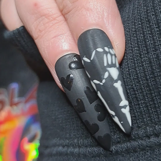 black gothic press on nails with alt black hearts and emo skeleton hands forming a heart nail art 