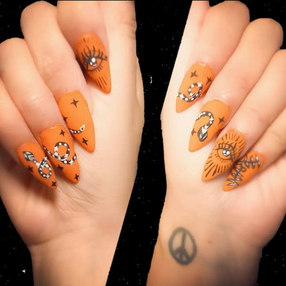 orange matte stick on nail extensions with witchy snakes vines and eye nail art 